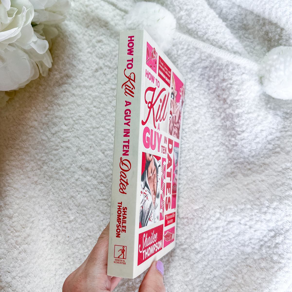 A hand holds a book titled "How to Kill a Guy in Ten Dates" by Shaillee Thompson. The book cover and spine feature a pink and red collage design with photos of a woman.