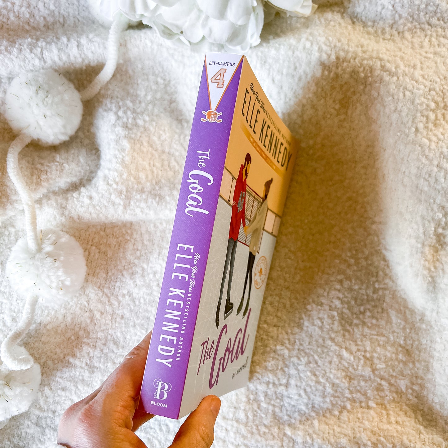 Book titled 'The Goal' by Elle Kennedy held against a soft, textured background