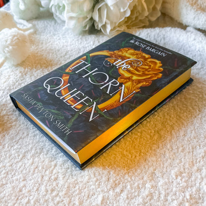 Book titled 'The Thorn Queen' by Sasha Peyton Smith on a textured surface with flowers in the background