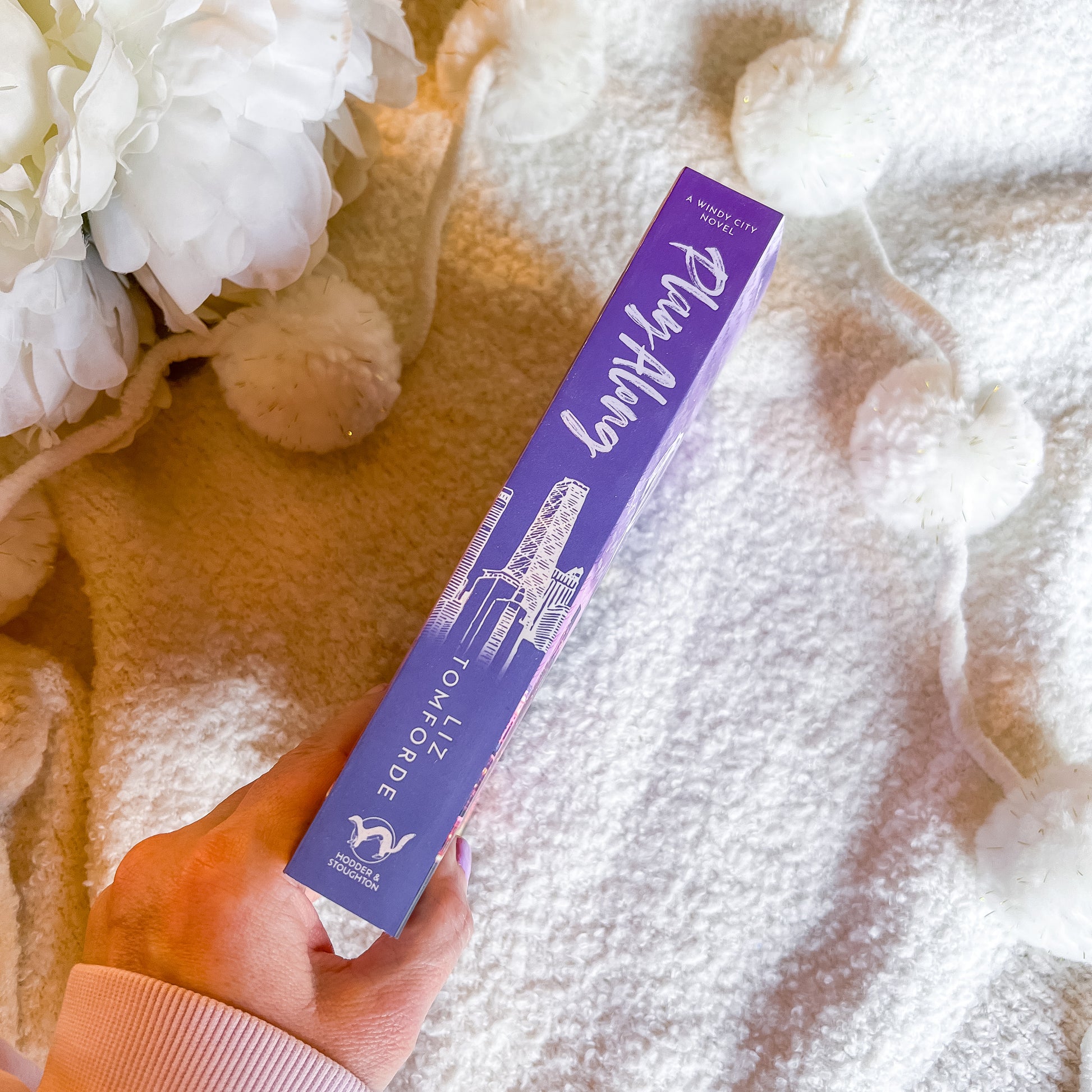 Hand holding the spine of "play along" against a textured white and gold background.
