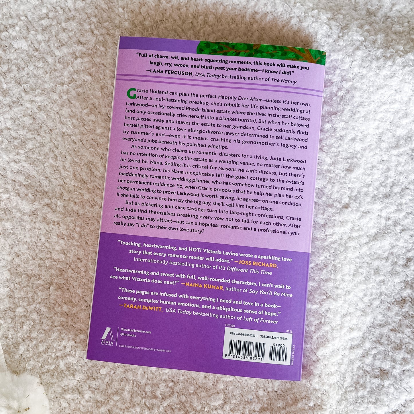 The back cover of a book back, featuring a purple background with white text and several colorful review quotes, photographed on a textured white fabric surface.