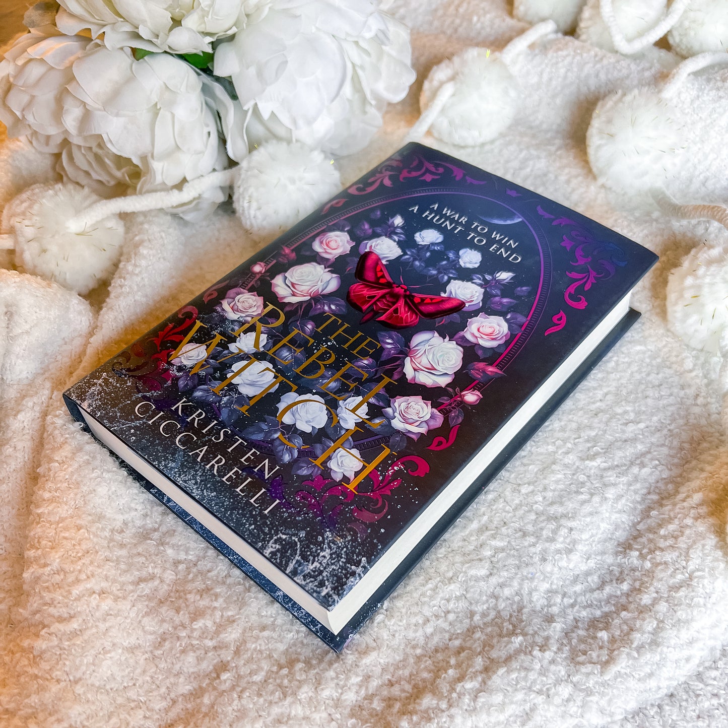 Book titled 'The rebel Witch' by Kristen Occarelli on a soft surface with flowers.
