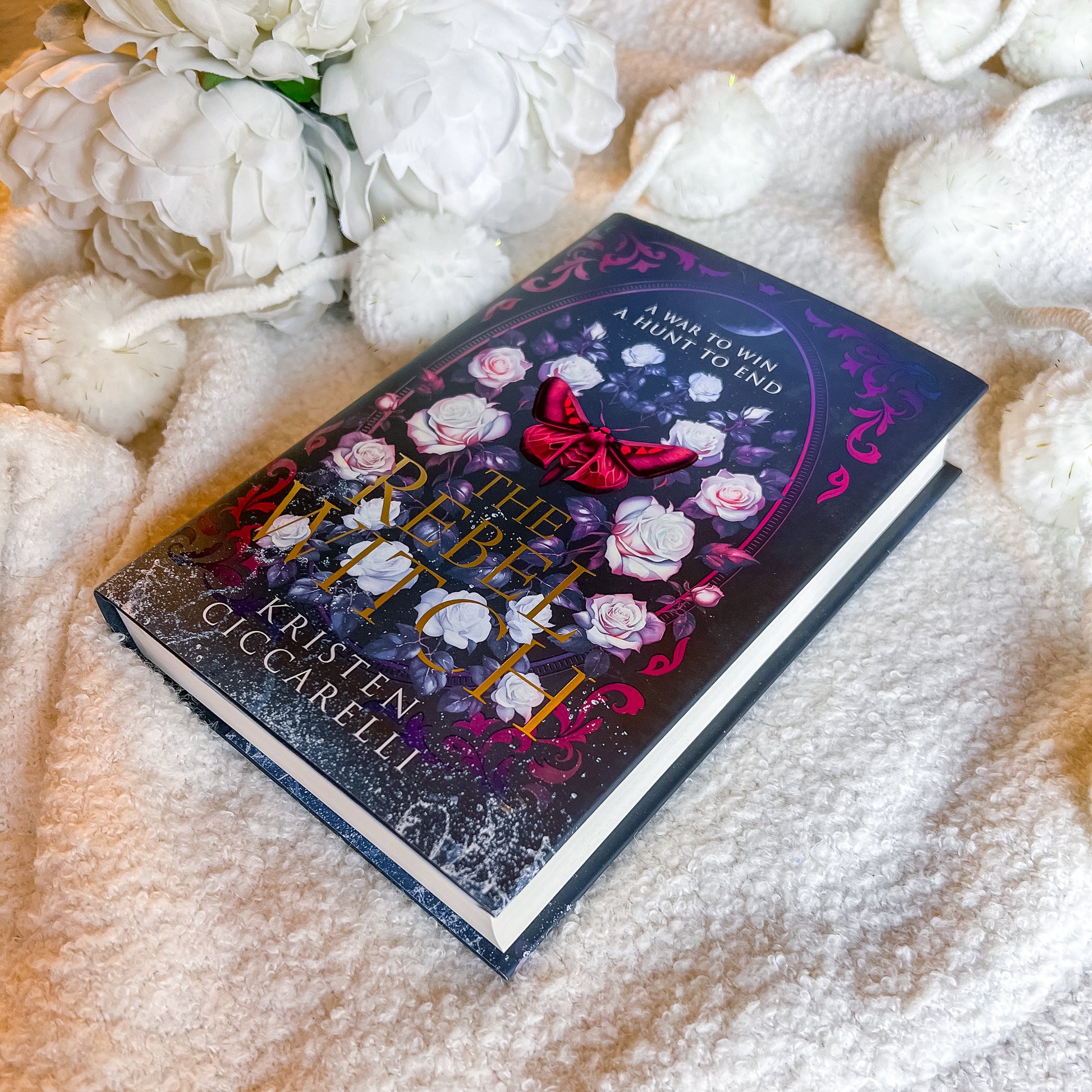 Book titled 'The rebel Witch' by Kristen Occarelli on a soft surface with flowers.
