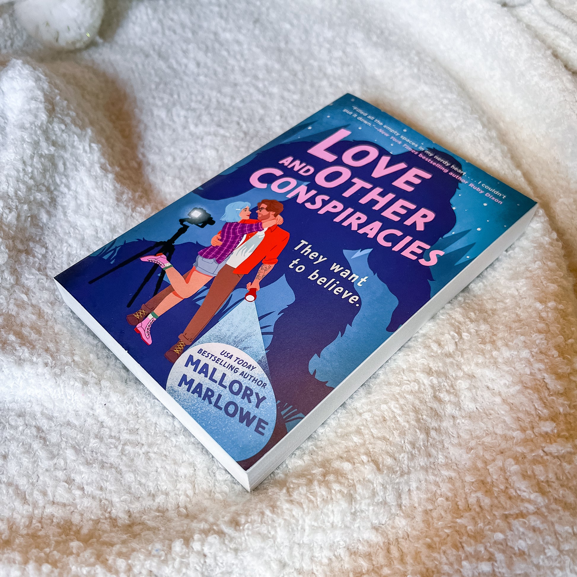 Book titled 'Love and Other Conspiracies' by Mallory Marlowe on a fluffy white surface