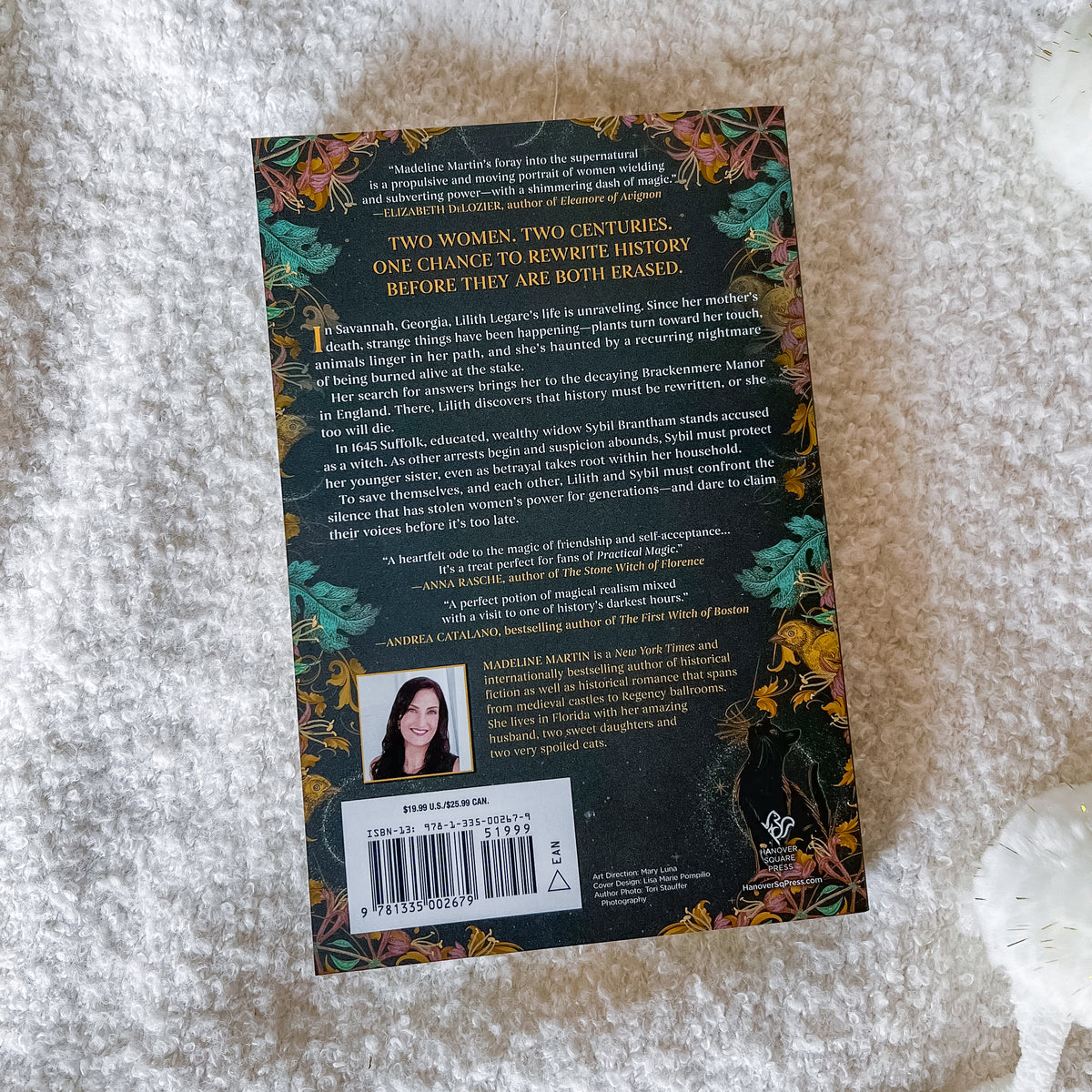 The back cover of the book 'Two Women, Two Centuries: One Chance to Rewrite History Before They Are Both Erased' by Marianna Martinez, displayed on a textured white faux fur surface.