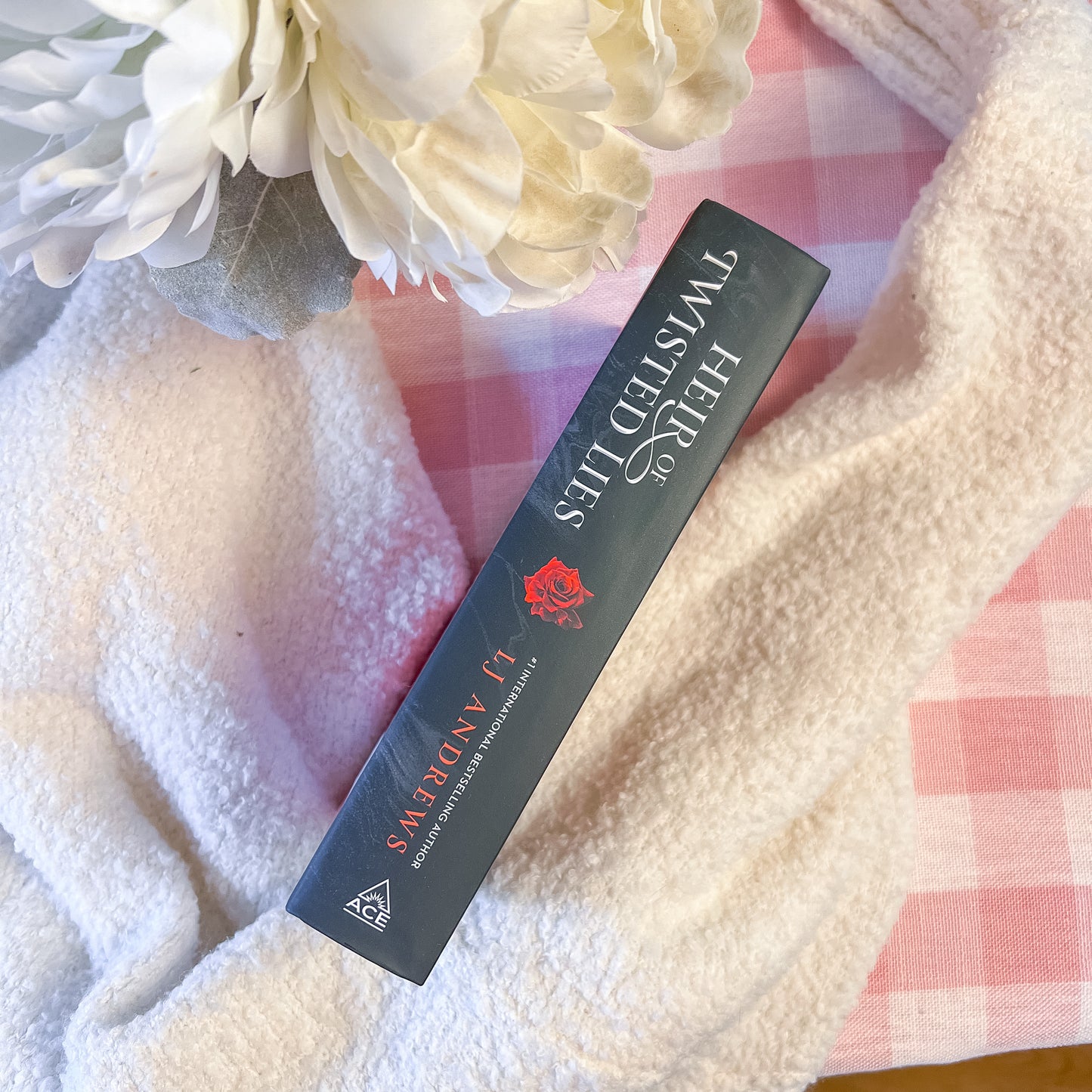 Spine of "heir of twisted lies" on a soft fabric background with flowers