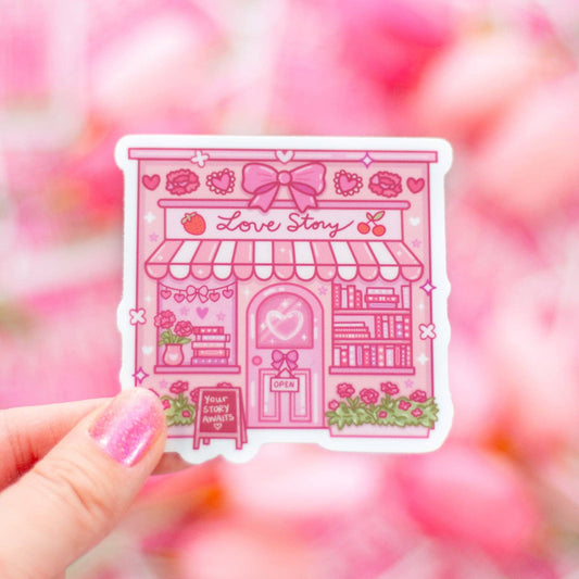 Pink 'Love Story' building sticker held by a hand with a blurred pink background