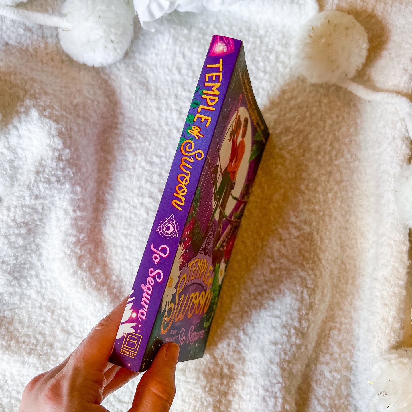 Hand holding a 'Temple of Swoon' book against a textured white background
