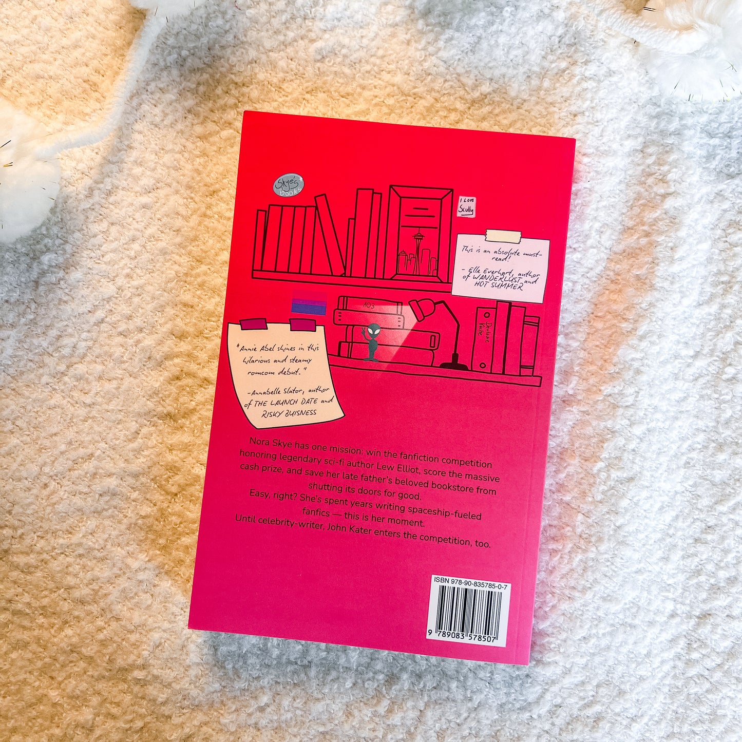 The back cover of a pink book , photographed flat on a textured cream-colored faux fur surface.