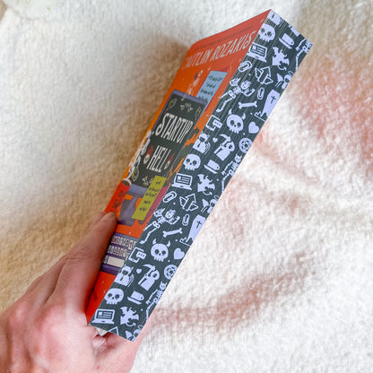 Book titled 'Startup Hell' held by a hand on a soft, light-colored surface