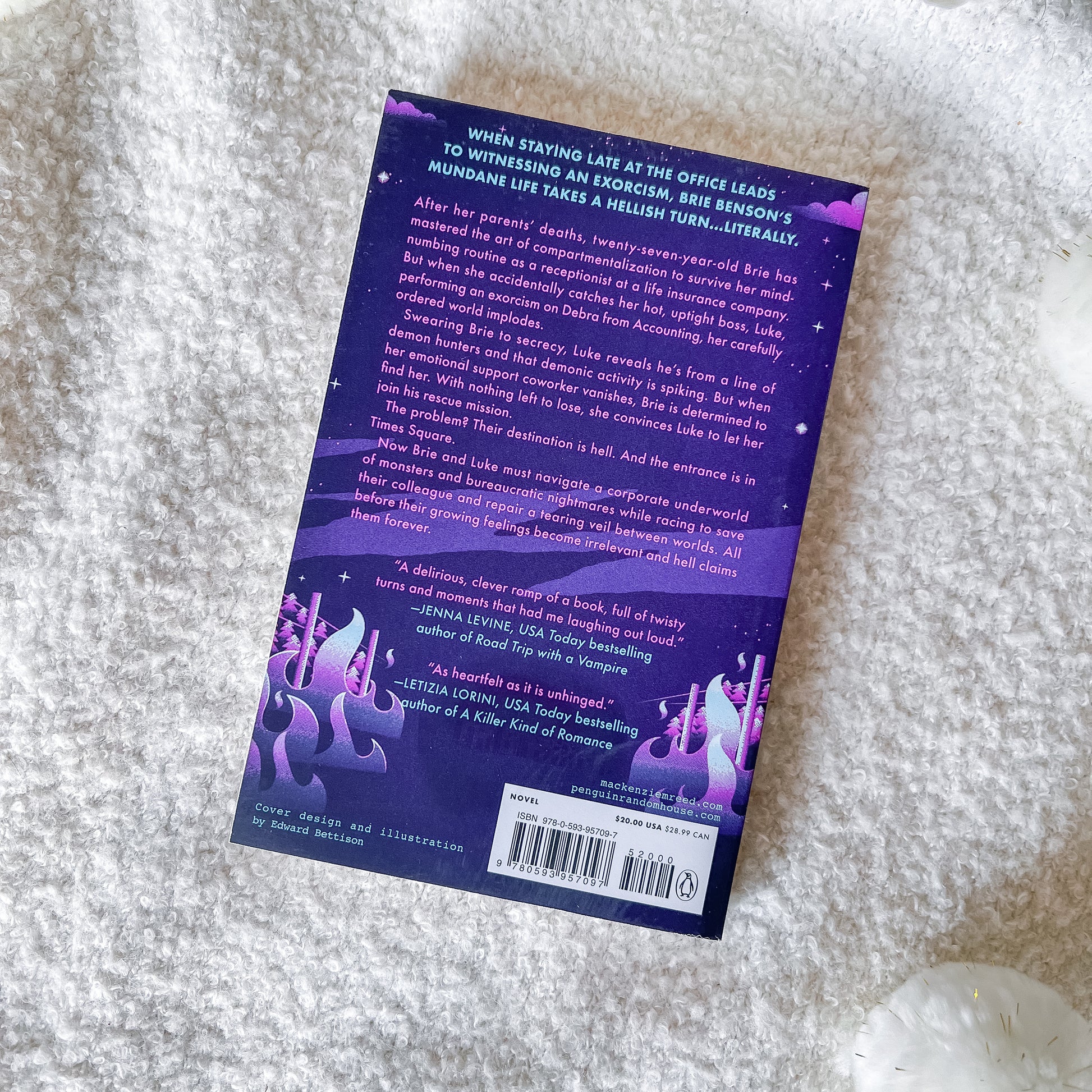 The back cover of the book featuring a purple and black cosmic fantasy illustration with glowing purple mushrooms and a white barcode label, photographed on a white textured faux fur surface.