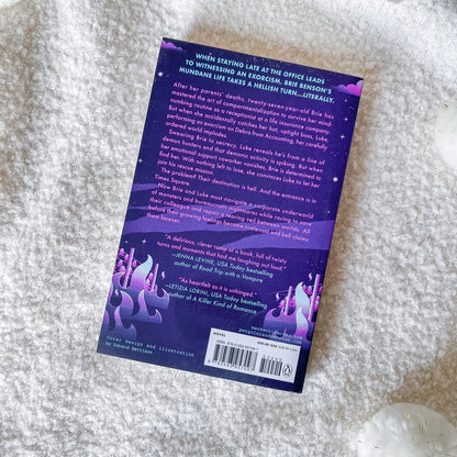 The back cover of the book featuring a purple and black cosmic fantasy illustration with glowing purple mushrooms and a white barcode label, photographed on a white textured faux fur surface.