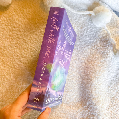 Purple book titled 'Fall with Me' by Becka Mack held against a textured beige background