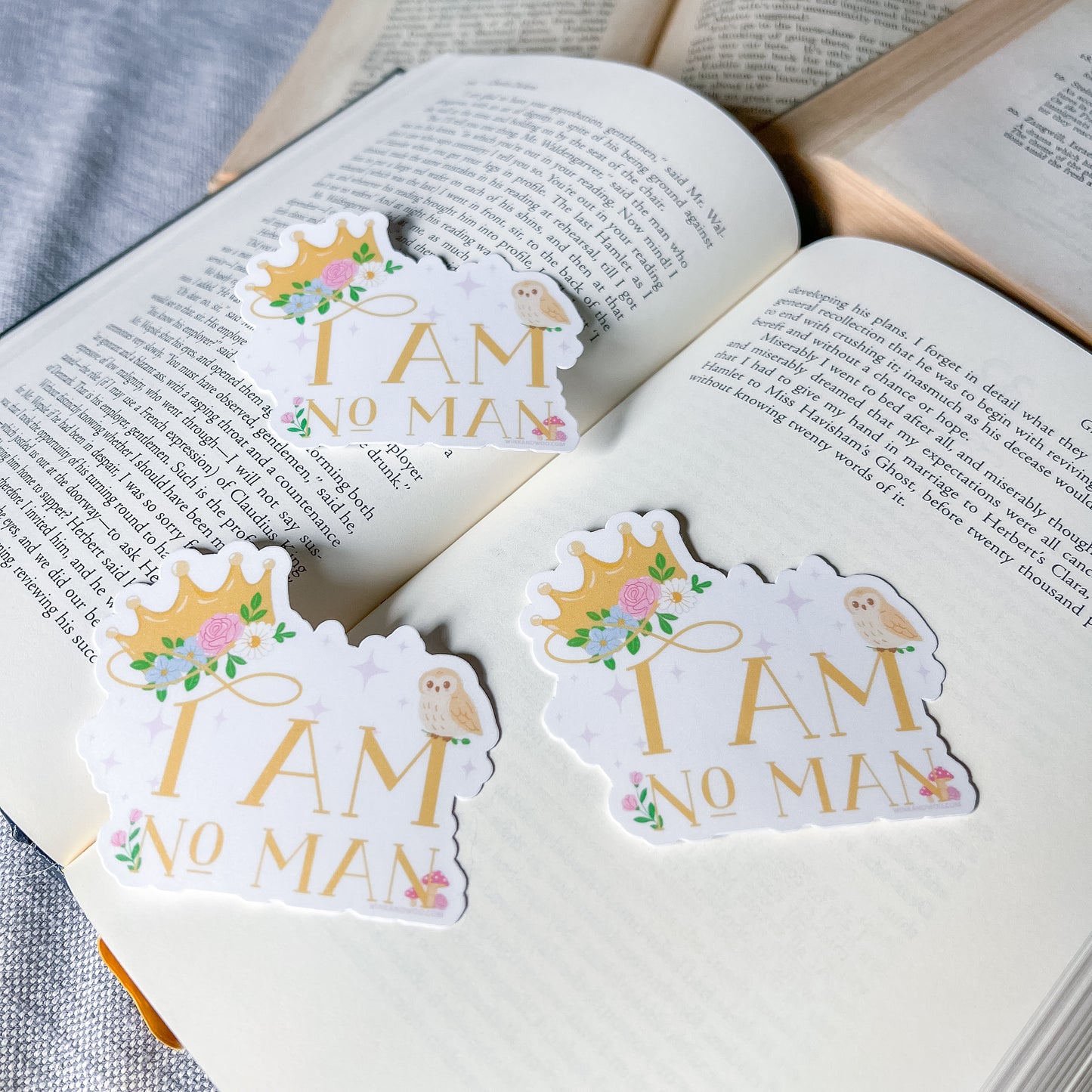 Three 'I AM NO MAN' stickers on an open book
