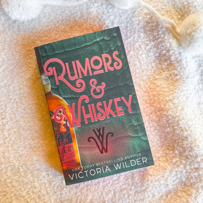 Book titled 'Rumors & Whiskey' by Victoria Wilder on a textured surface