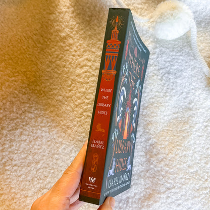 Book titled 'Where the Library Hides' held against a textured beige background