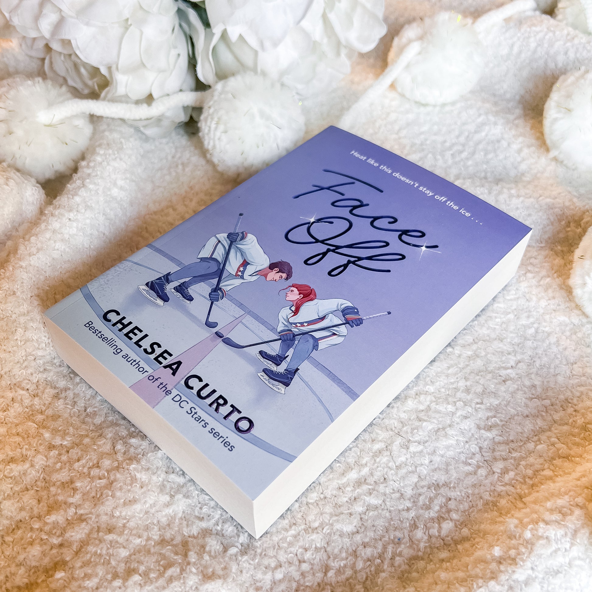 Book titled 'Face Off' by Chelsea Curto on a soft, textured surface with white flowers.