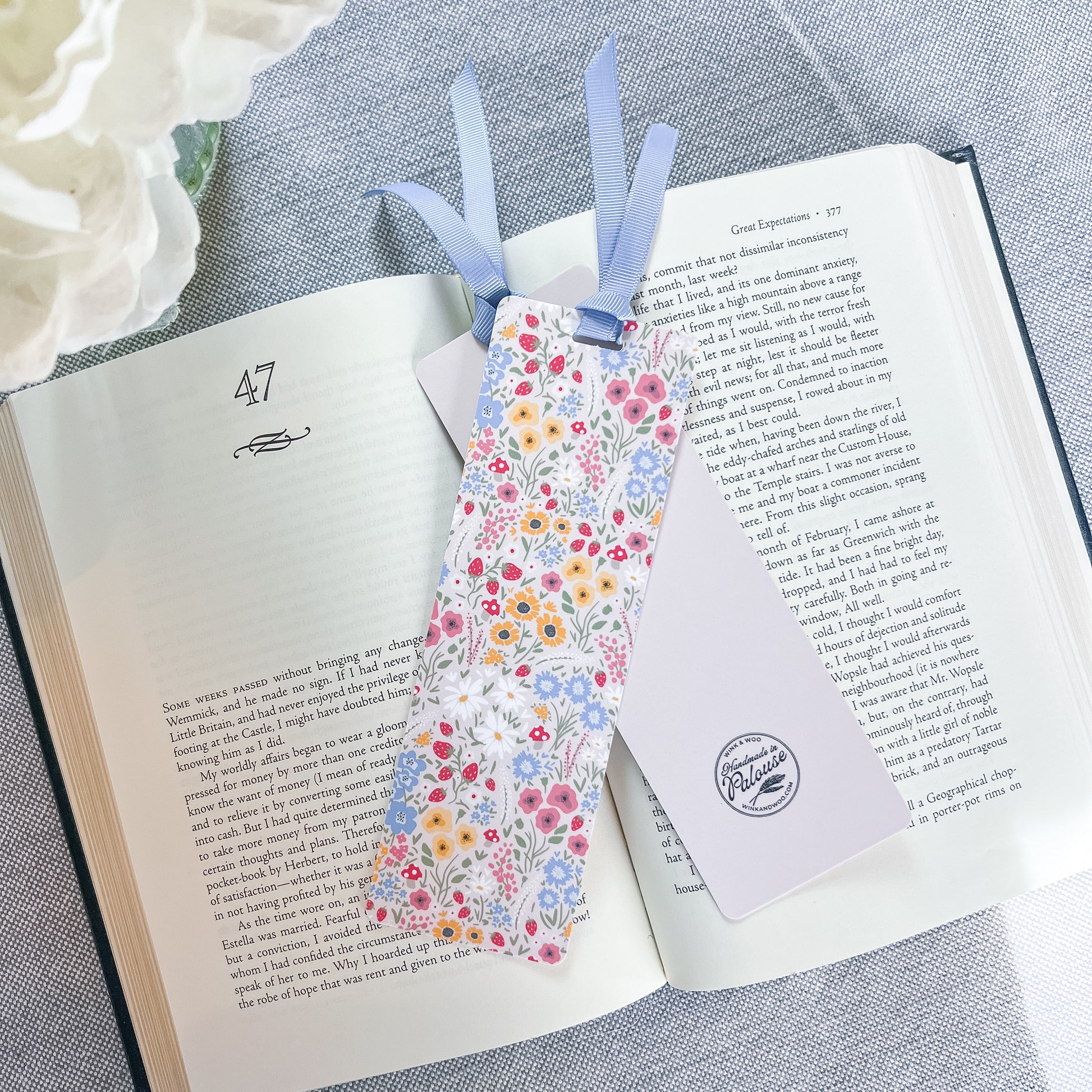 Floral bookmark with a blue ribbon sitting on top of a book