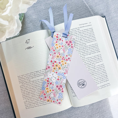 Floral bookmark with a blue ribbon sitting on top of a book