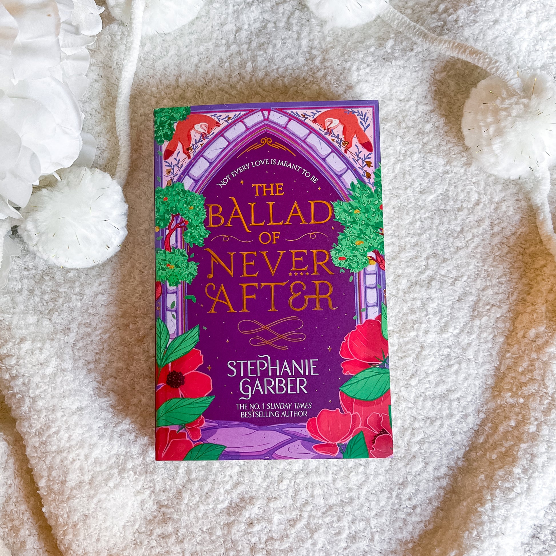 Book titled 'The Ballad of Never After' by Stephanie Garber on a textured surface.