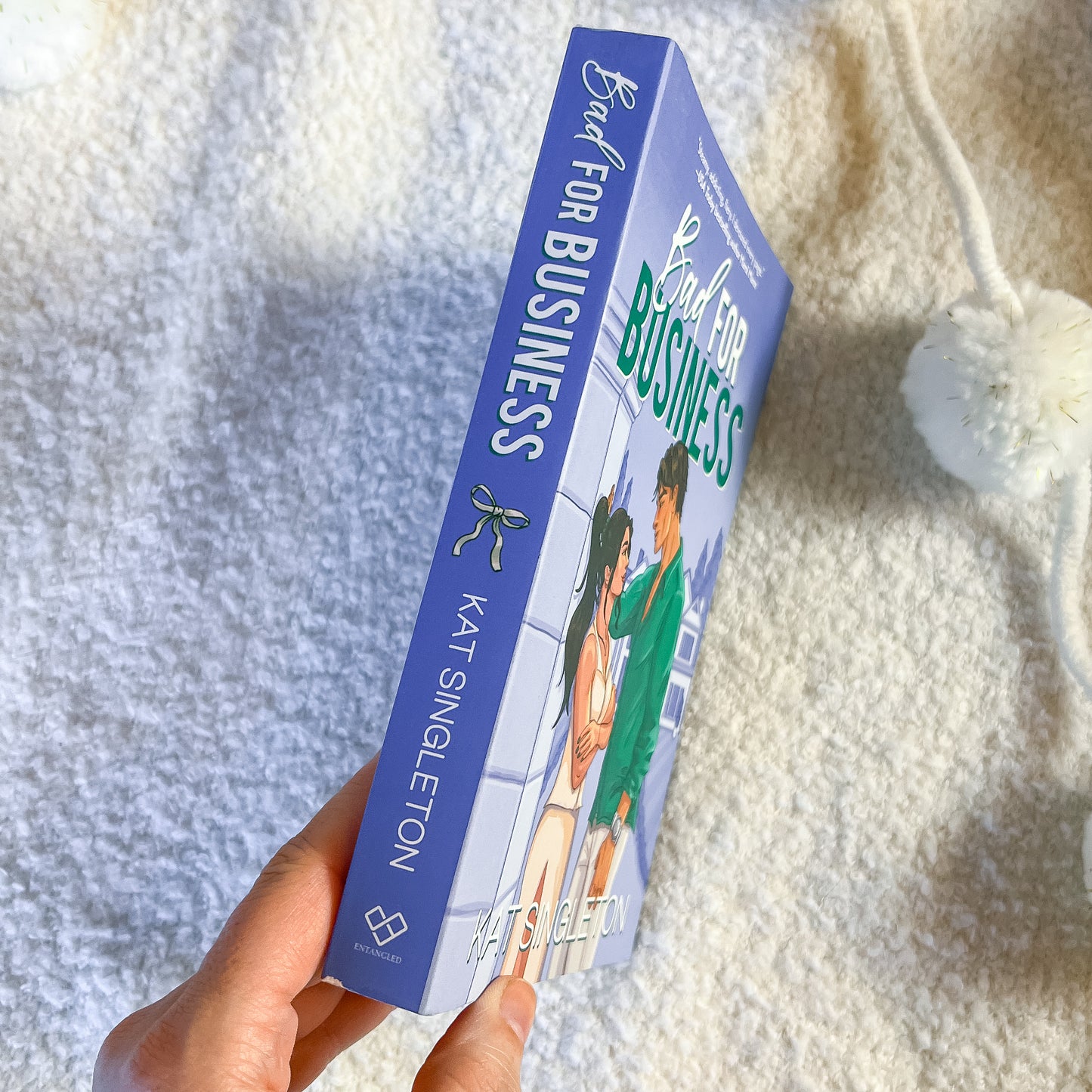 Book titled 'Bad for Business' by Kat Singleton held against a textured white background
