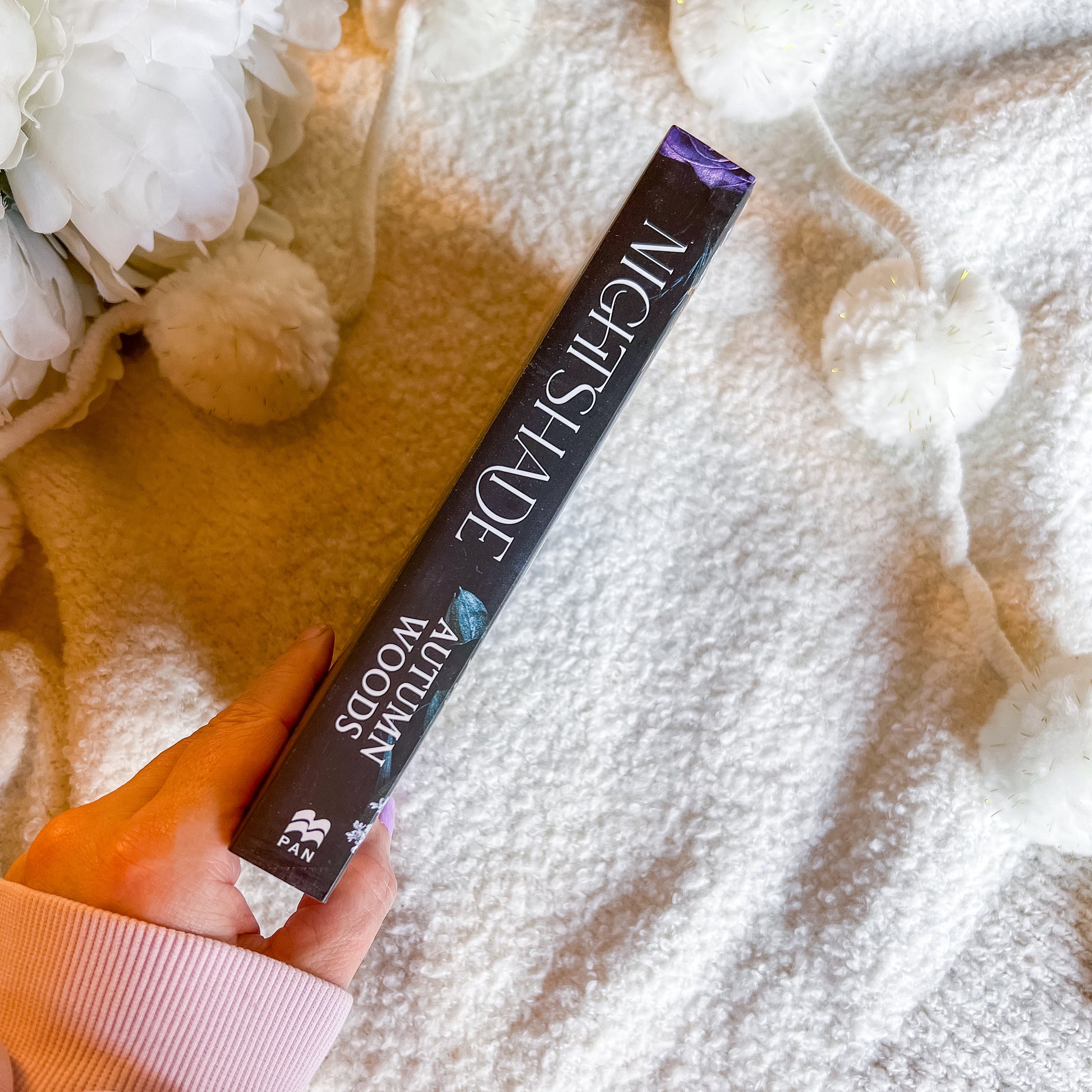 Hand holding a book spine with 'Nightshade' on a textured surface.