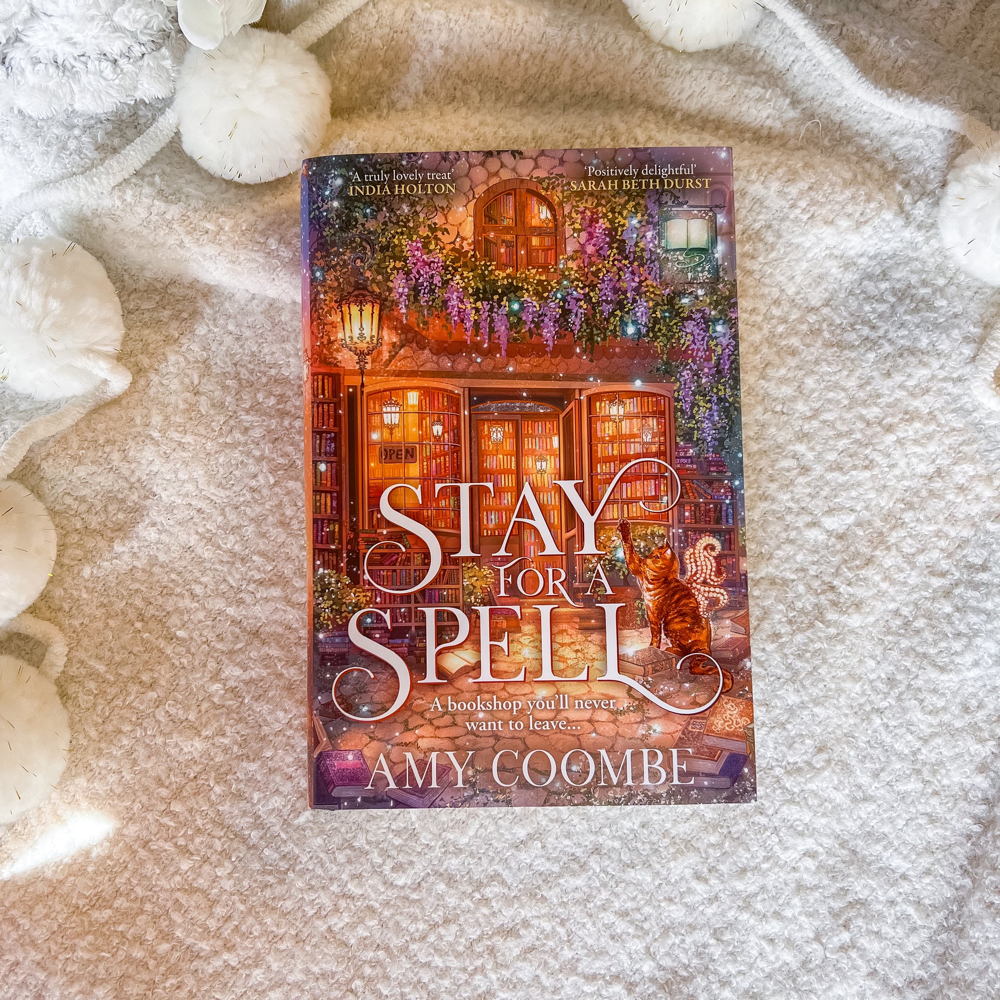 Book titled 'Stay for a Spell' by Amy Coombe on a textured surface with decorative elements.