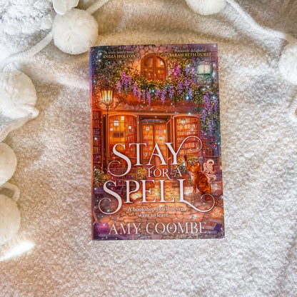 Book titled 'Stay for a Spell' by Amy Coombe on a textured surface with decorative elements.