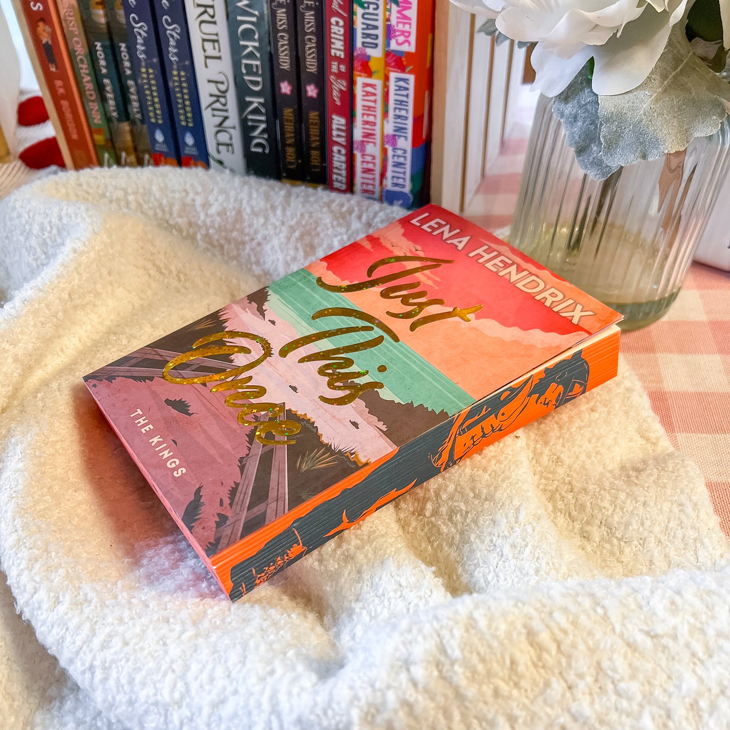 Book titled 'Just This Once' by Lena Hendrix on a textured surface with books in the background.