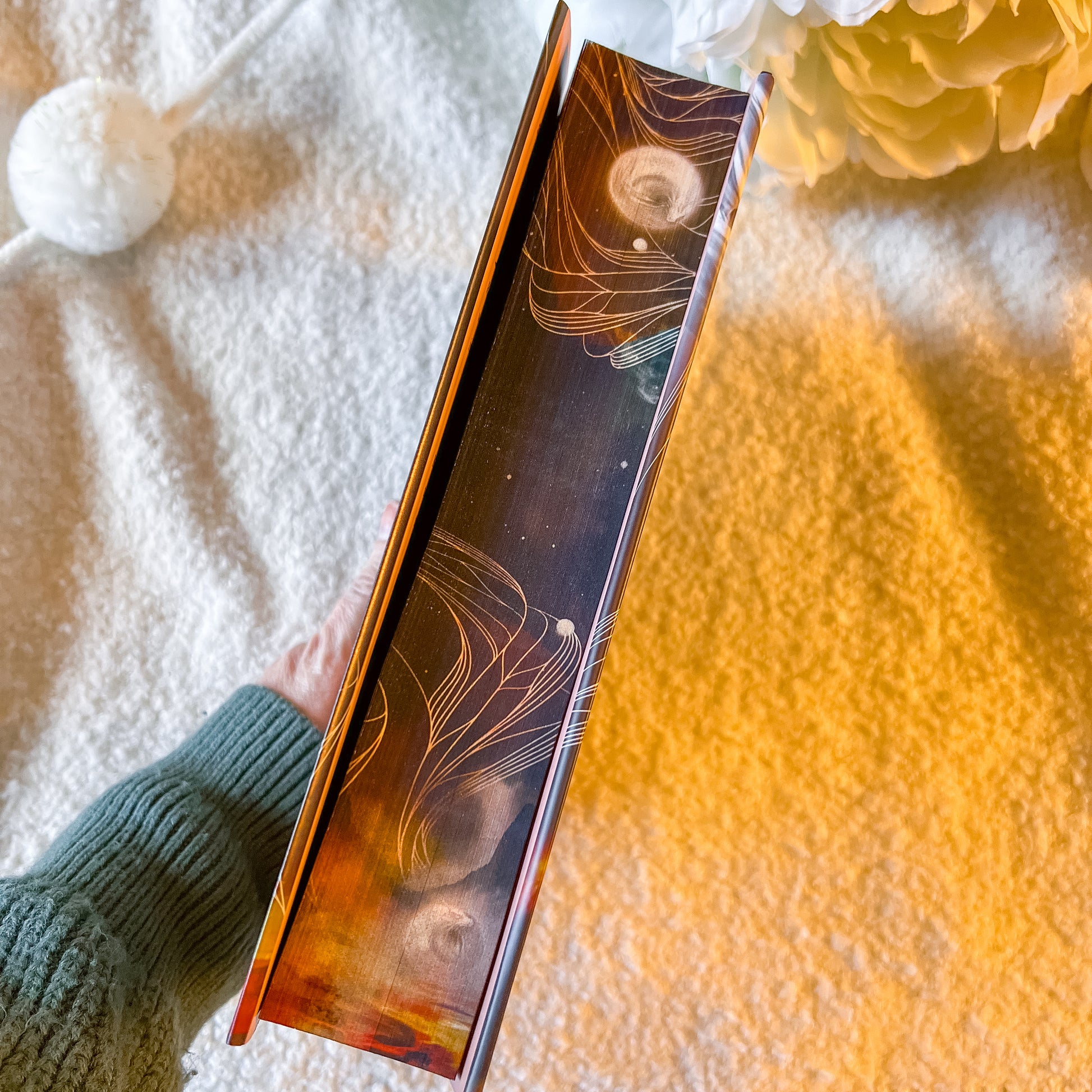 Person holding a decorative book with celestial design on a textured surface