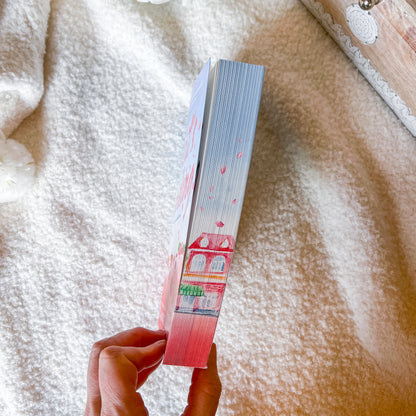 Hand holding a book with a colorful cover against a soft, textured background