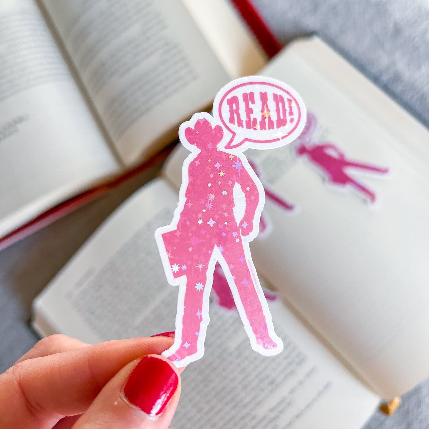 Pink silhouette of a person with a 'READ!' speech bubble held over an open book.