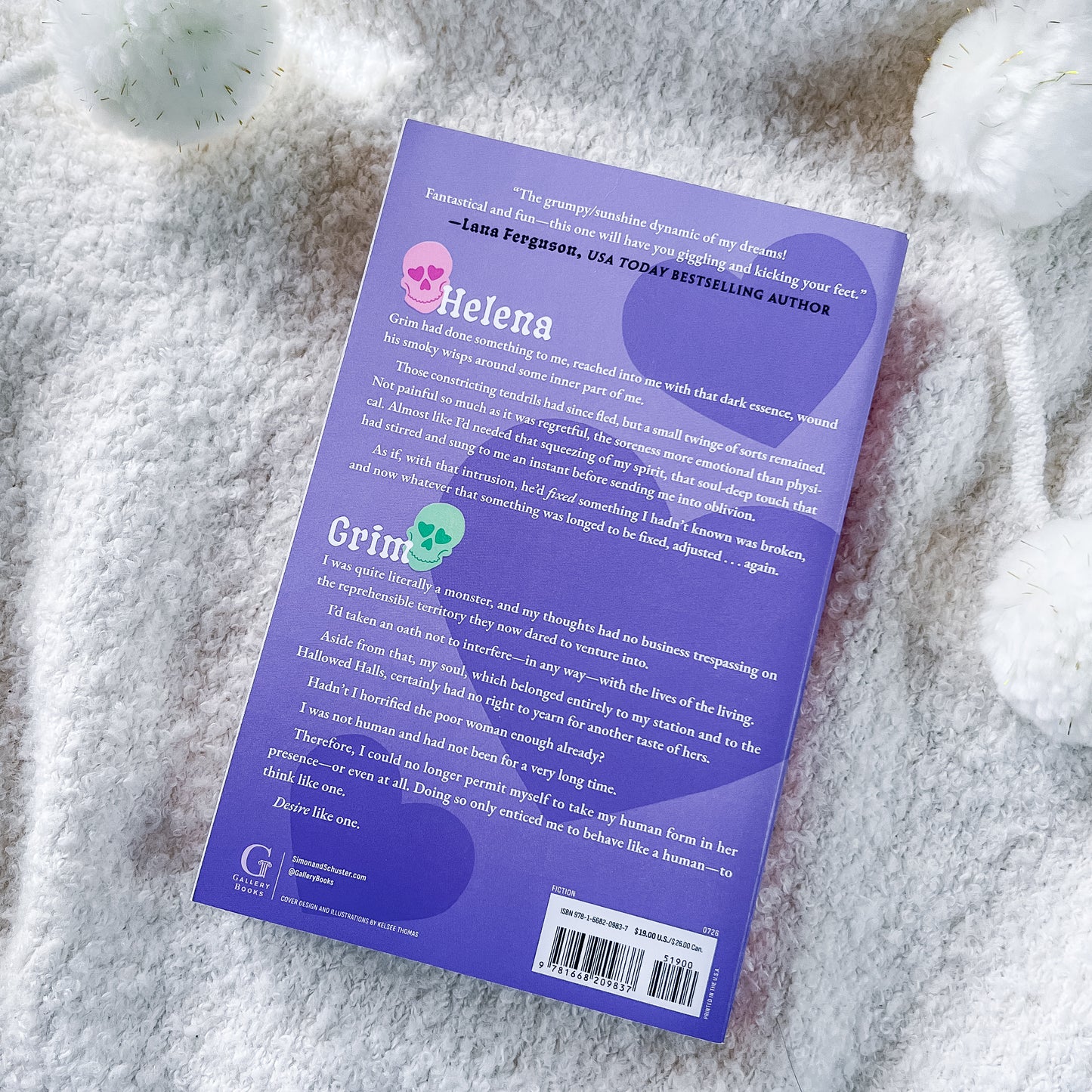 The back cover of the book. The book is placed on a soft, white, textured blanket with decorative white stones in the background.
