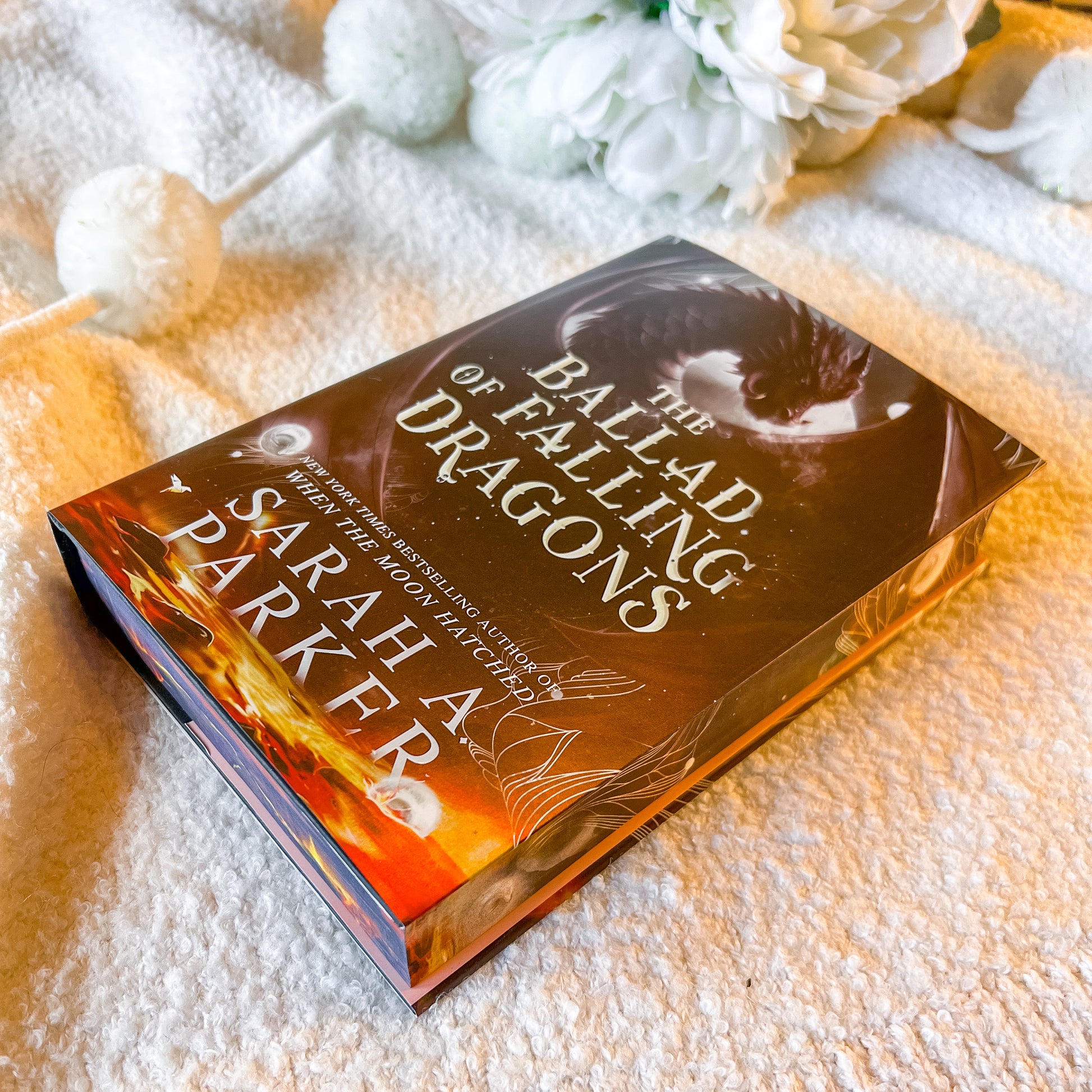 Book titled 'The Ballad of Falling Dragons' by Sarah A. Parker on a textured surface with decorative elements.