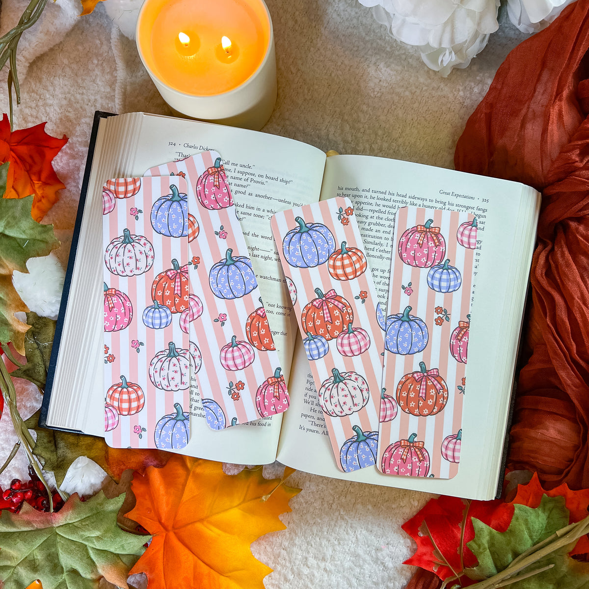 A group of bookmarks with a pumpkin-themed design, styled on an open book with a warm blanket background.