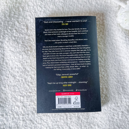 The back cover of the book, featuring a black background with white text, a red 'SUBSCRIBE' banner, and a barcode, photographed on a white textured blanket.