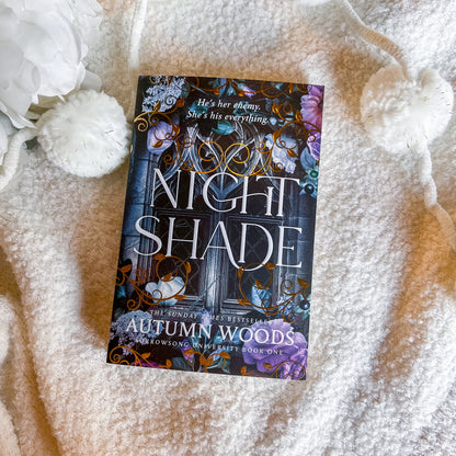Book titled 'Nightshade' by Autumn Woods on a textured surface with decorative elements.