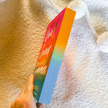 Book titled 'Our Secret Summer' held against a textured fabric background