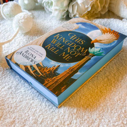 Book titled 'His Kingdom Will Not Kill Me' by Ilona Andrews on a textured surface with decorative elements.