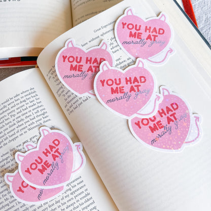 Pink stickers with 'You had me at morally grey' text on an open book
