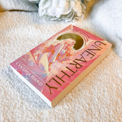 Book titled 'Unearthly' by Cynthia Hand on a textured surface with flowers in the background