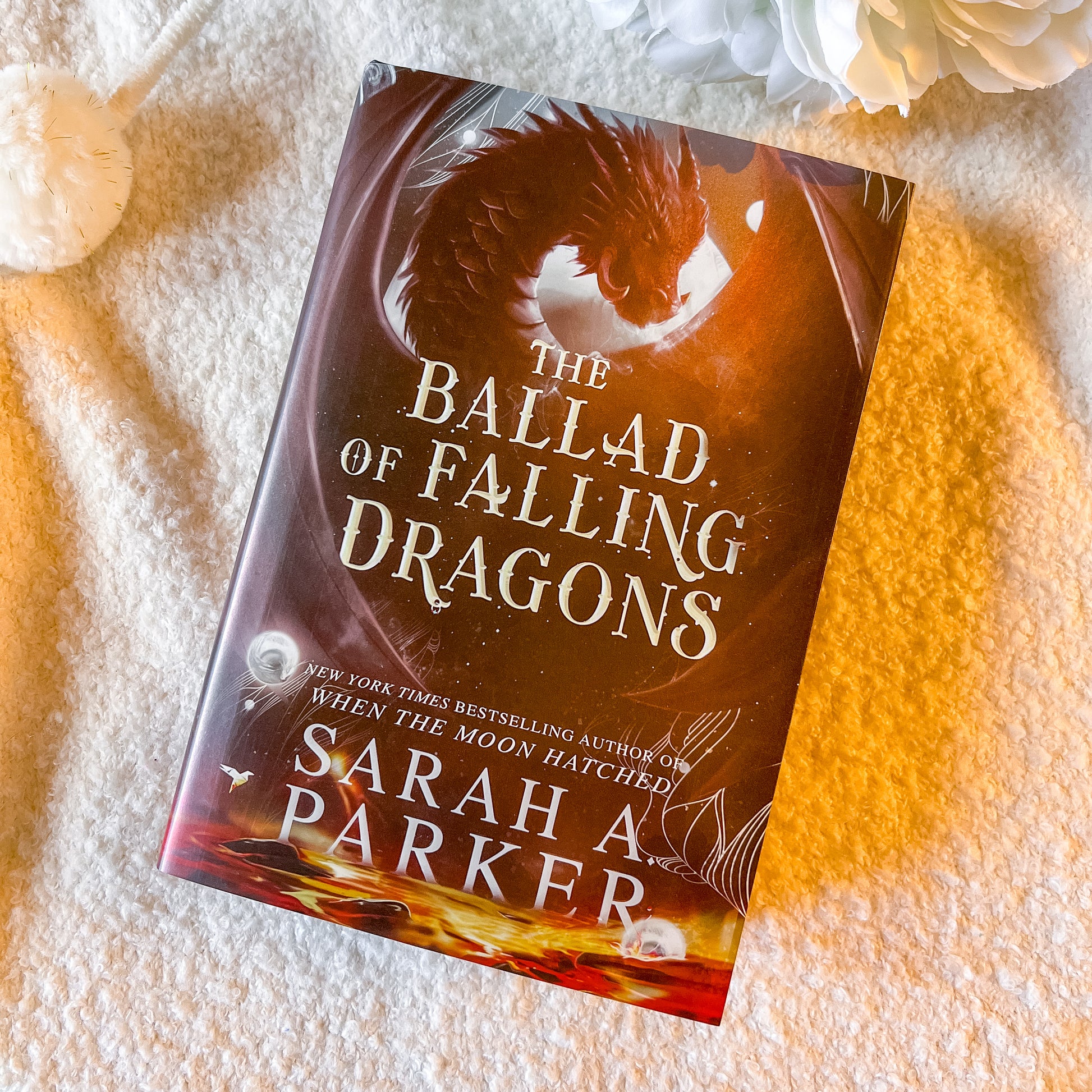 Book titled 'The Ballad of Falling Dragons' by Sarah A. Parker on a textured surface.