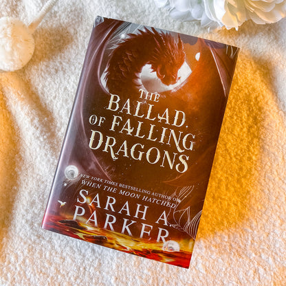 Book titled 'The Ballad of Falling Dragons' by Sarah A. Parker on a textured surface.