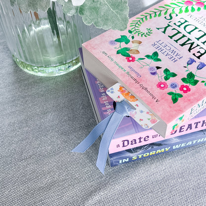 Floral and cat patterned bookmark with a blue ribbon tucked into a book.