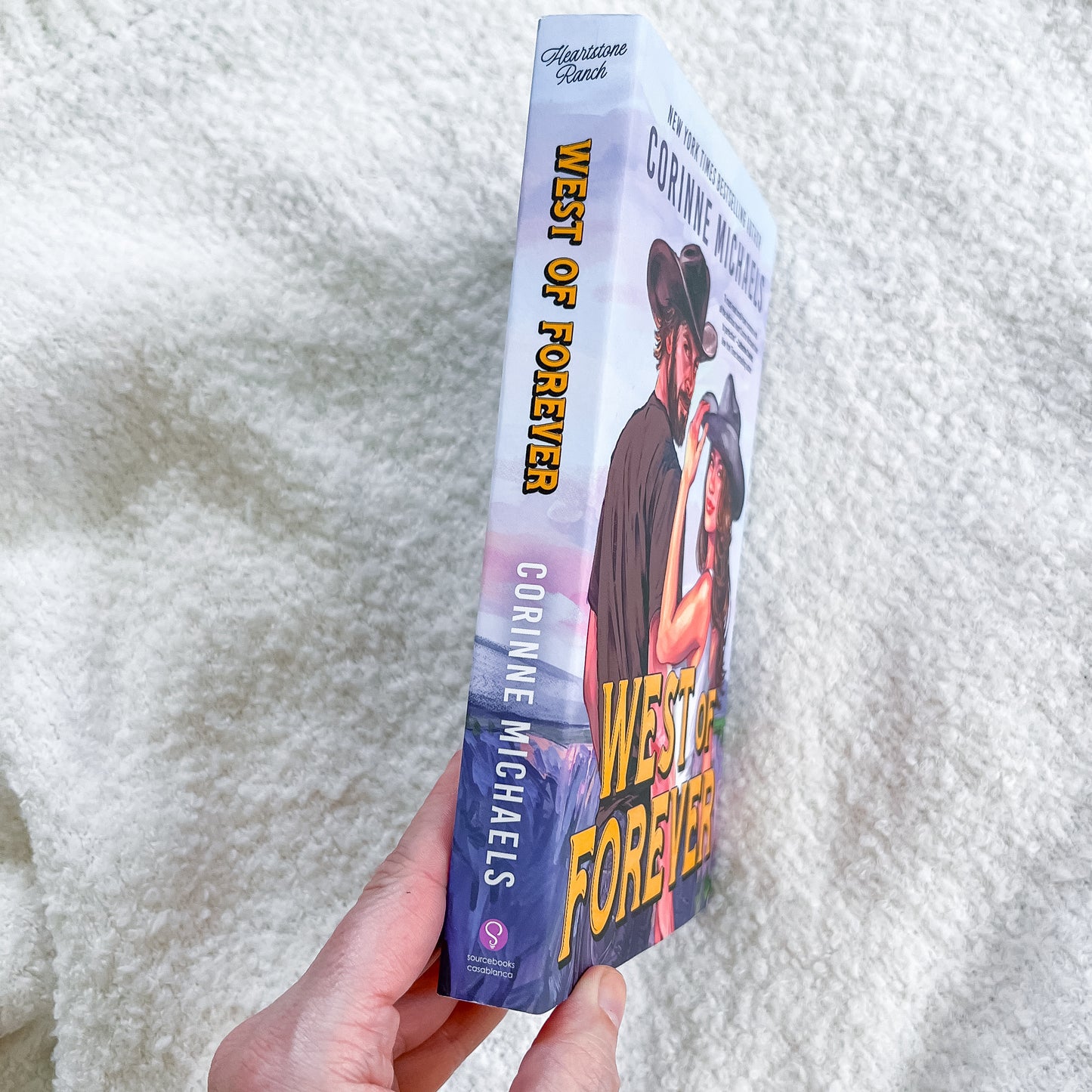 Book titled 'West of Forever' by Corinne Michaels held against a white textured background