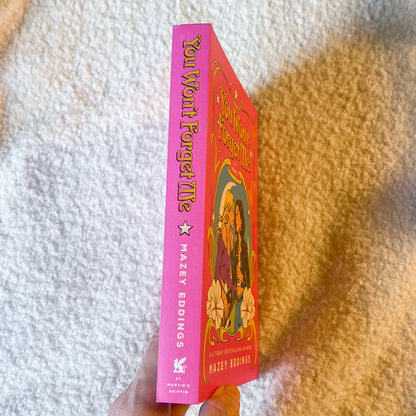 Pink book titled 'You Won't Forget Me' by Hazel Eddings on a textured white and brown background