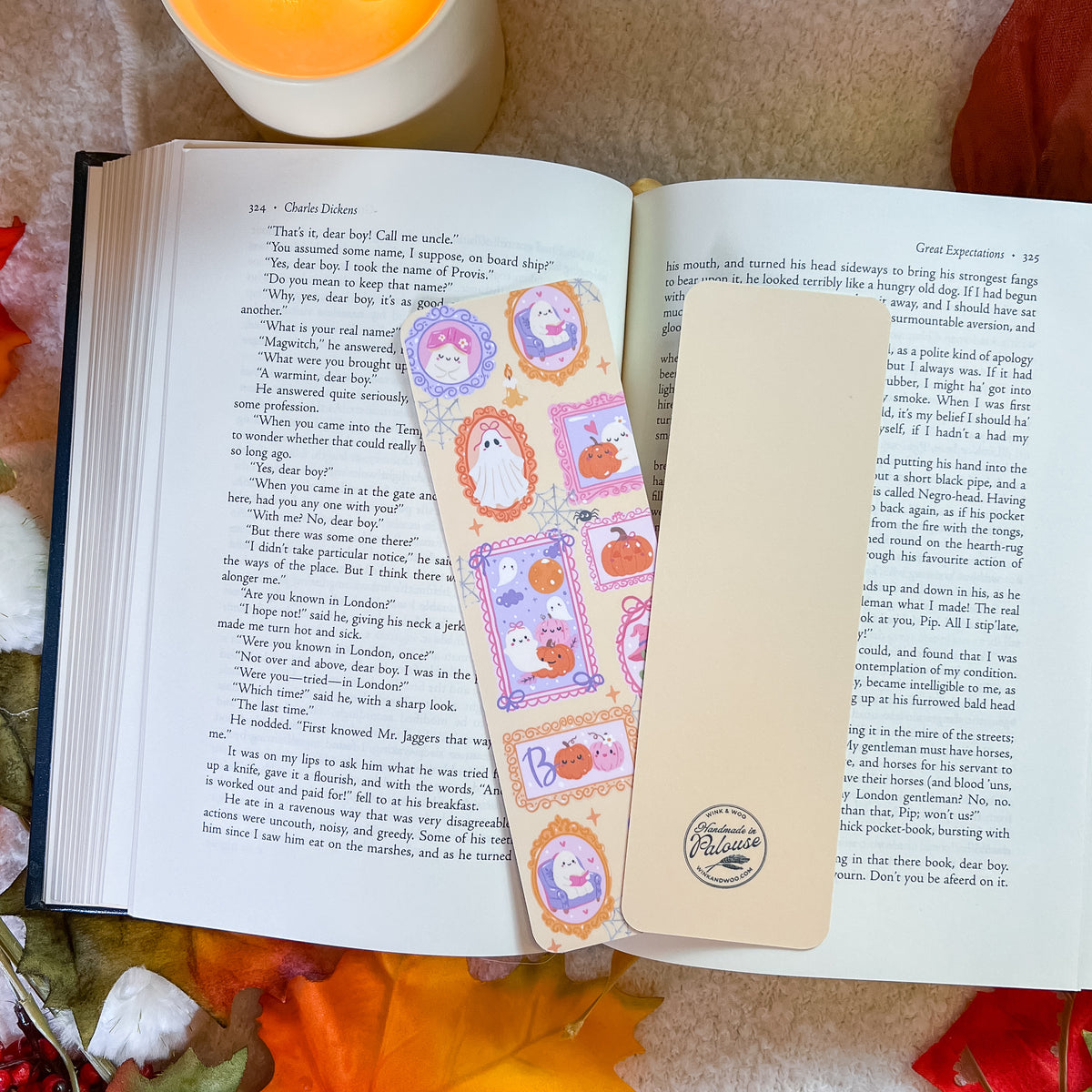 An open book spread on a wooden surface, featuring decorative illustrated page protectors with cartoon characters and pastel borders over printed text. The scene is styled with autumn leaves and warm natural light.