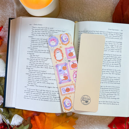 An open book spread on a wooden surface, featuring decorative illustrated page protectors with cartoon characters and pastel borders over printed text. The scene is styled with autumn leaves and warm natural light.
