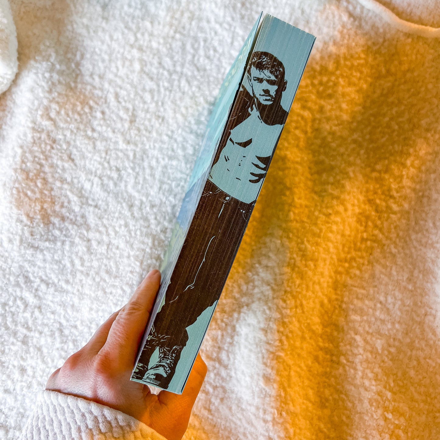 Book with a cover featuring a stylized illustration of a person held by a hand on a textured surface.