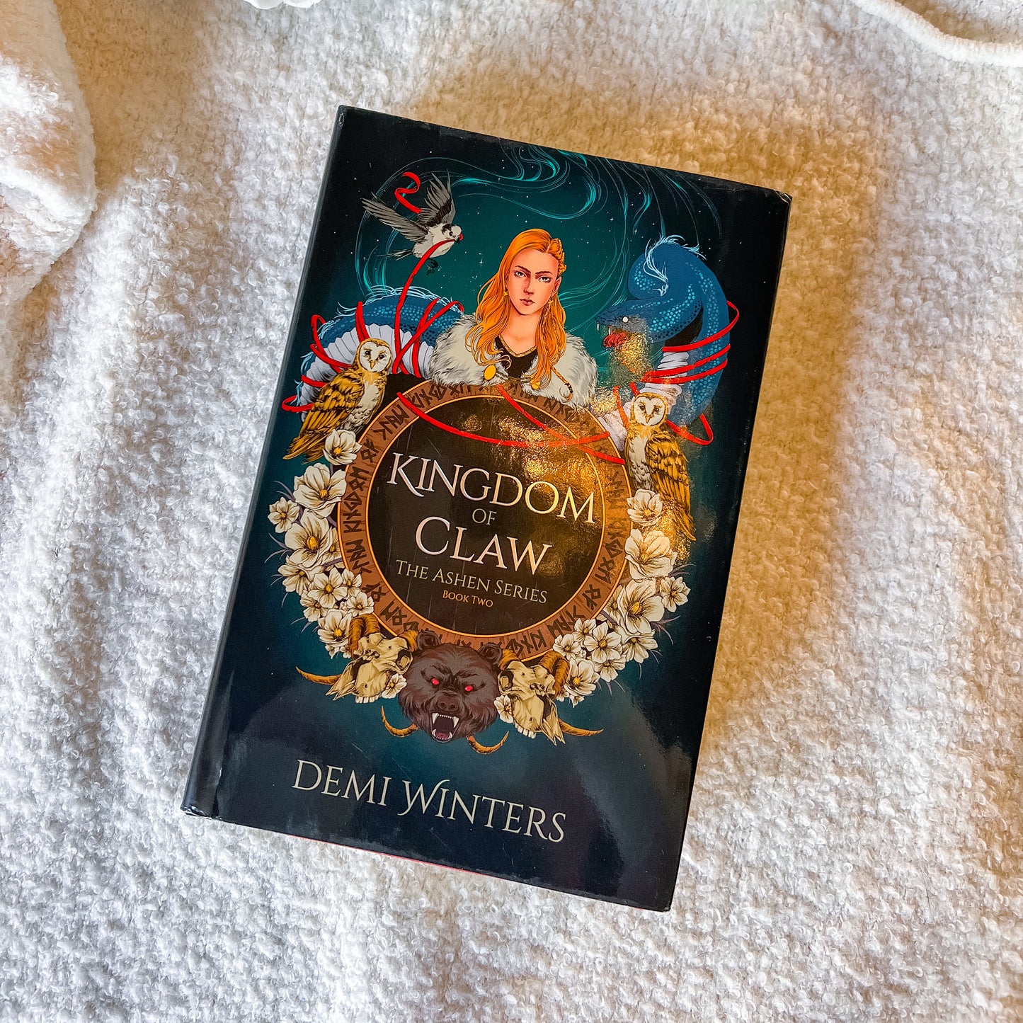 Book titled 'Kingdom of Claw' by Demi Winters on a textured white surface